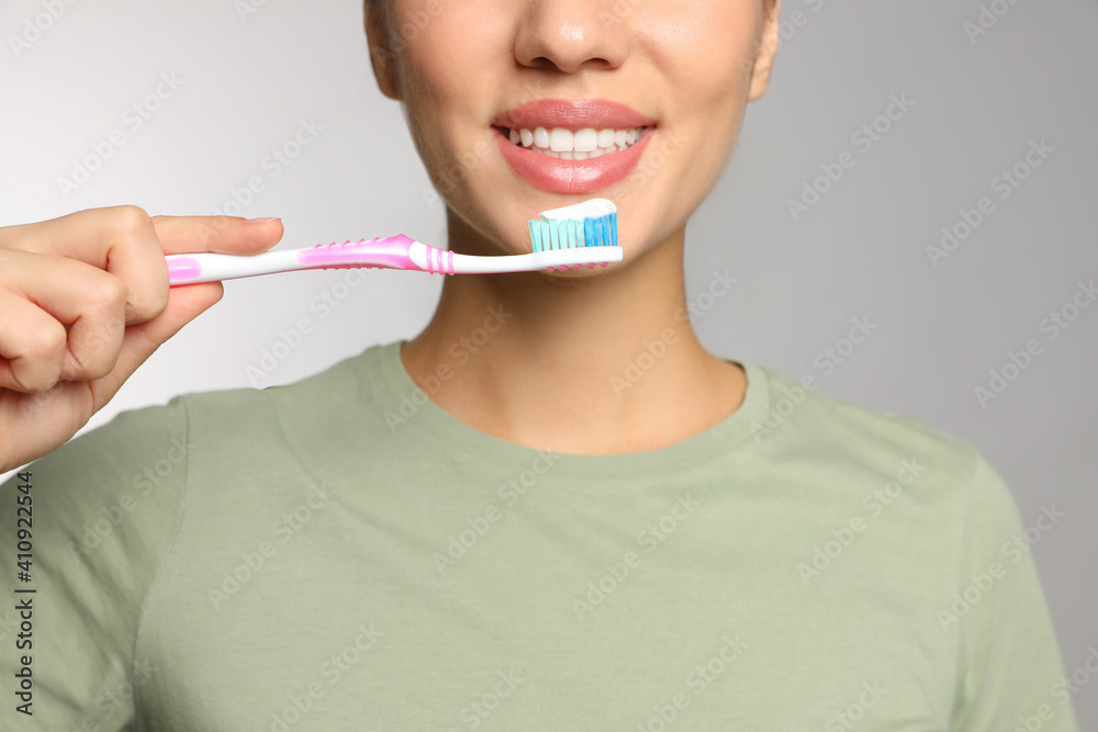 Woman holding toothbrush with paste on light background, closeup Woman holding toothbrush with paste on light background, closeup