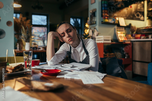 overworked manager dealing with finances in her restaurant photo