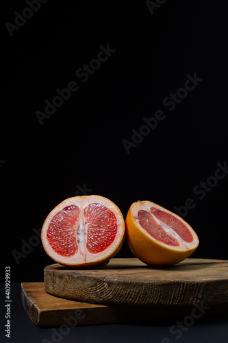 Grapefruit on a black background. Grapefruit cut in half on a wooden board. Citrus fruit. Exotic fruit