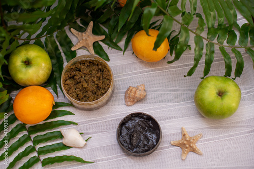 Fototapeta Naklejka Na Ścianę i Meble -  image of homemade cosmetics ingredients. aroma theme. Black mask, clay. organic cosmetics with extracts of herbs apples, lemons and oranges on white leaf green background