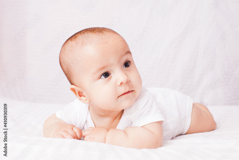 Adorable baby lying on the stomach at the white