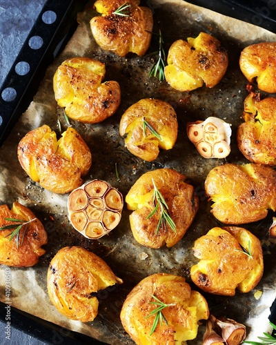 Broken potatoes baked with rosemary on a baking sheet