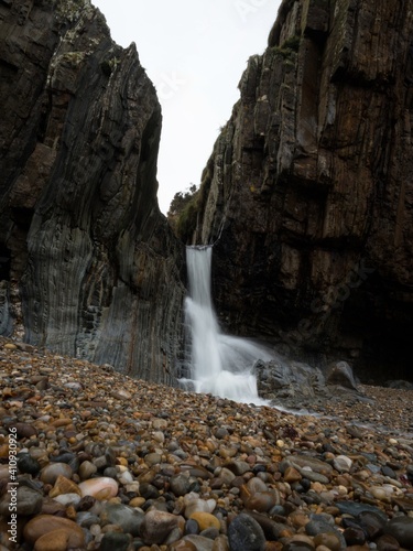 Waterfall long exposure at Playa del Silencio Gavieiro beach ocean sea coast shore cliffs in Castaneras Asturias Spain photo
