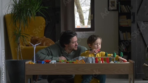 little boy playing with his father in the trains on the table at home