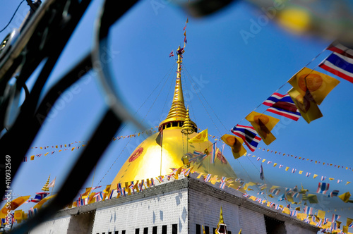 The Gold sanctuary decorated with small Thai Flags and Thai Buddhist Flags at Wat Luang Pho Ophasi temple in Bang mod district, Bangkok Thailand