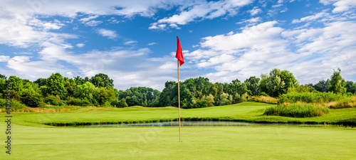 Golf course on a summer day with a flag, green golf with red flag