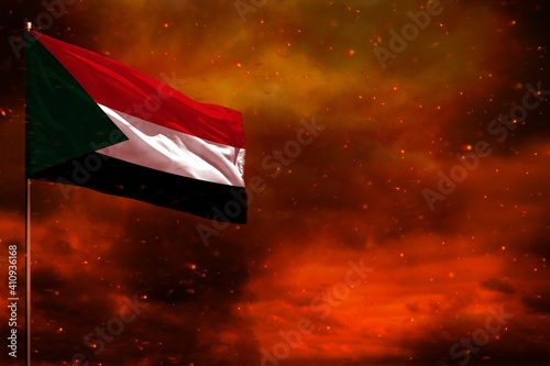 Fluttering Sudan flag mockup with blank space for your text on crimson red sky with smoke pillars background. Troubles concept.