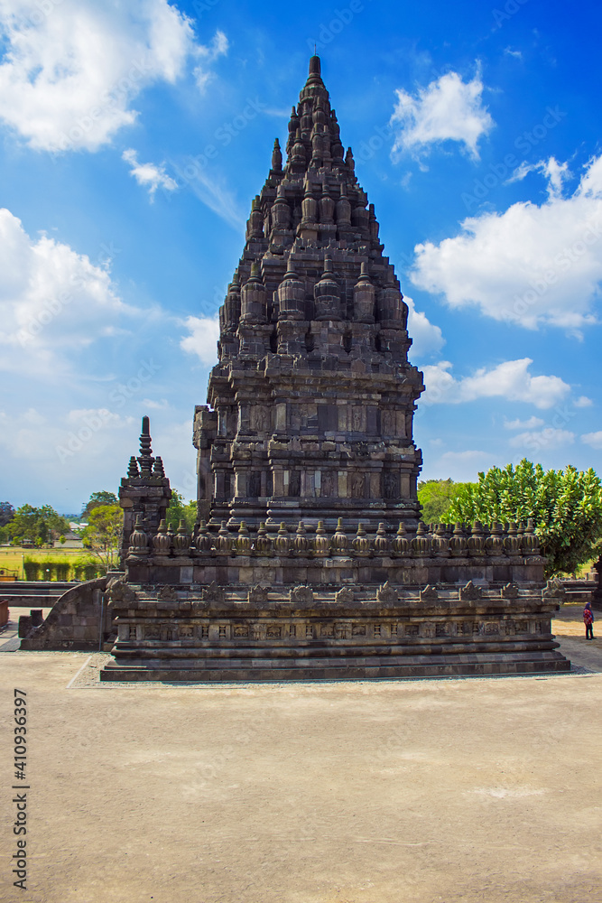 Prambanan Hindu temple view, green grass field foreground and blue sky near Yogyakarta, Java island, Indonesia