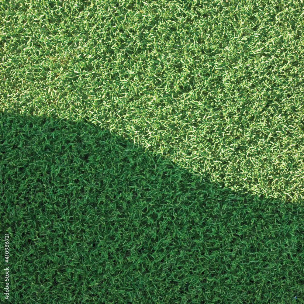 Obraz premium Artificial grass fake turf synthetic lawn field macro closeup, gentle shaded shadow area, green sports astroturf texture, vertical textured background pattern, large detailed shade