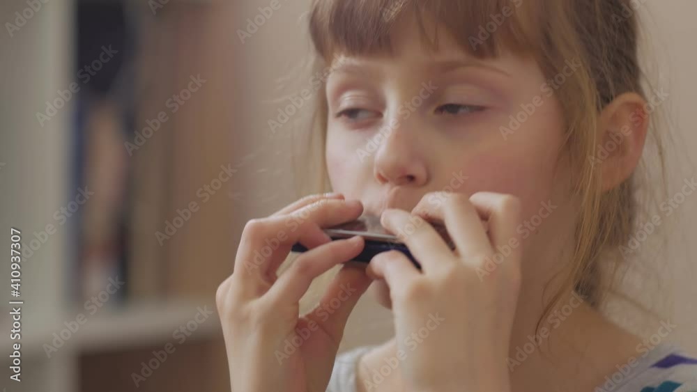 Cheerful girl playing the harmonica home interior closeup Cheerful girl playing the harmonica home interior closeup