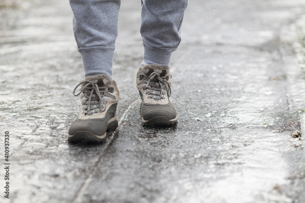 A pedestrian walks along a dangerous icy sidewalk. Frozen rain. A pedestrian walks along a dangerous icy sidewalk. Frozen rain.