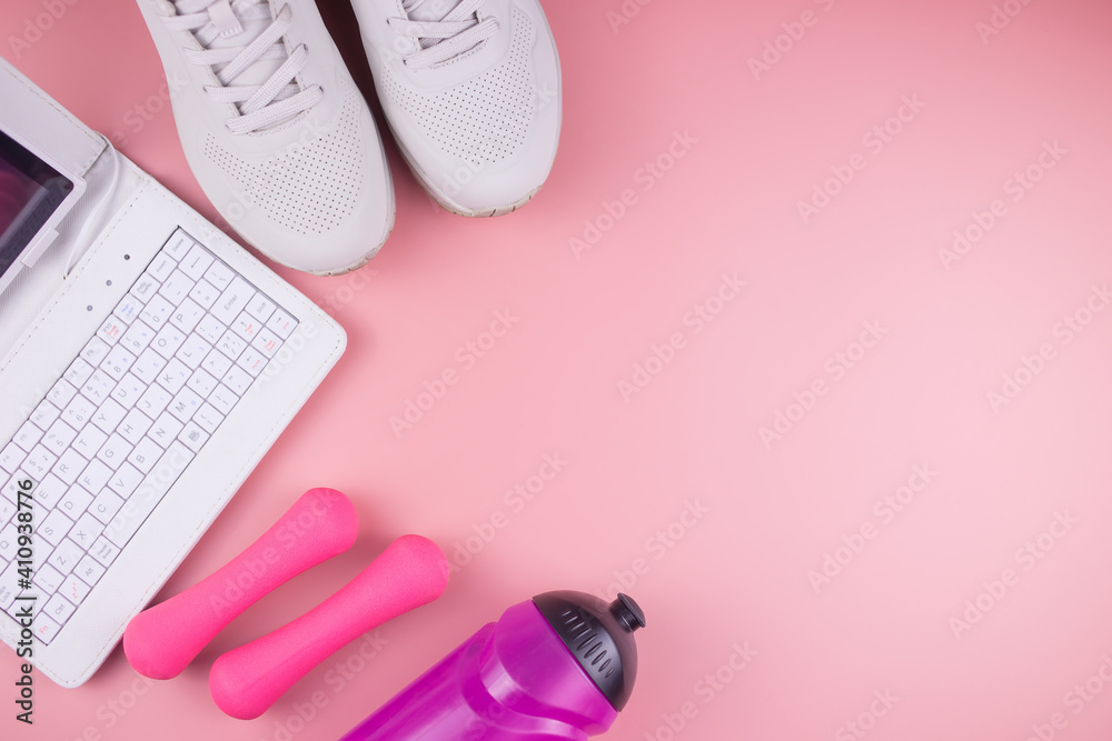 Online fitness. Sneakers, laptop, fitness bracelet, water bottle and dumbbells, on a pink background, workout online. Online fitness. Sneakers, laptop, fitness bracelet, water bottle and dumbbells, on a pink background, workout online.