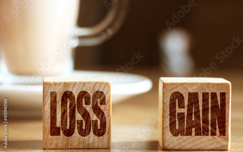 Wooden blocks on wooden table with Loss and Gain words. business concept.