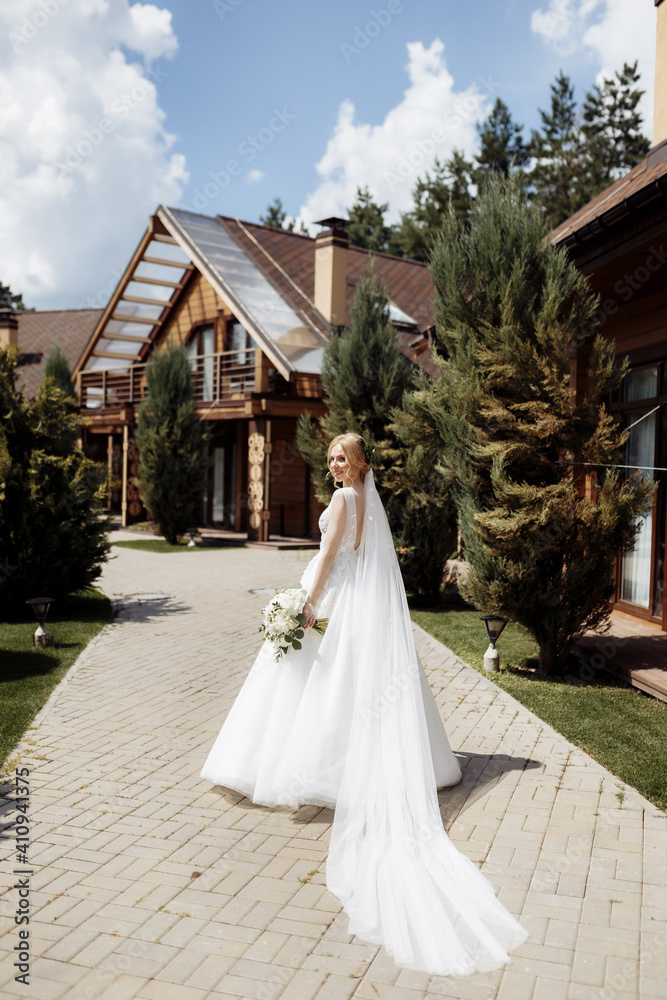 Fototapeta premium bride in a dress standing in a green garden and holding a wedding bouquet of flowers and greenery
