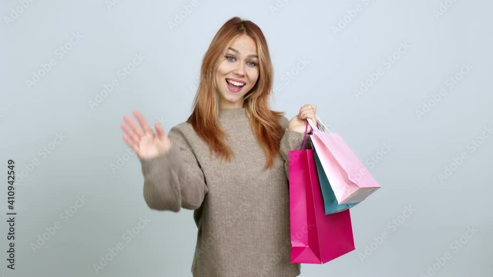 Teenager girl holding shopping bags saluting with hand with happy expression over isolated background Teenager girl holding shopping bags saluting with hand with happy expression over isolated background