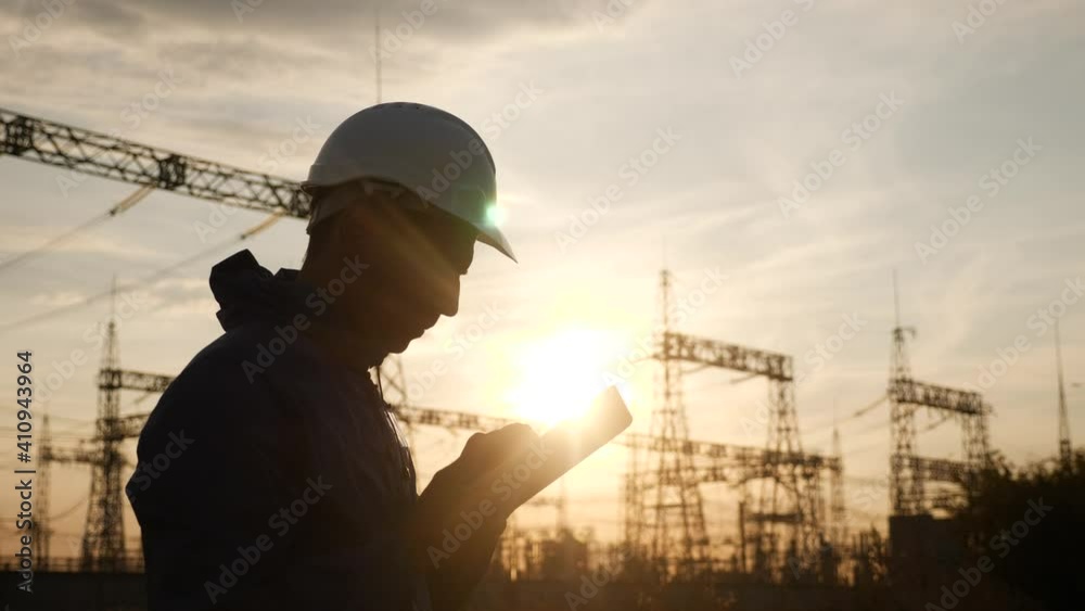 electrical worker silhouette engineer a working with digital tablet, near tower with electricity. energy business technology industry concept. electrical studying reading documents power on tablet