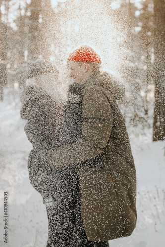 Young couple playing with snow and kissing and hugs