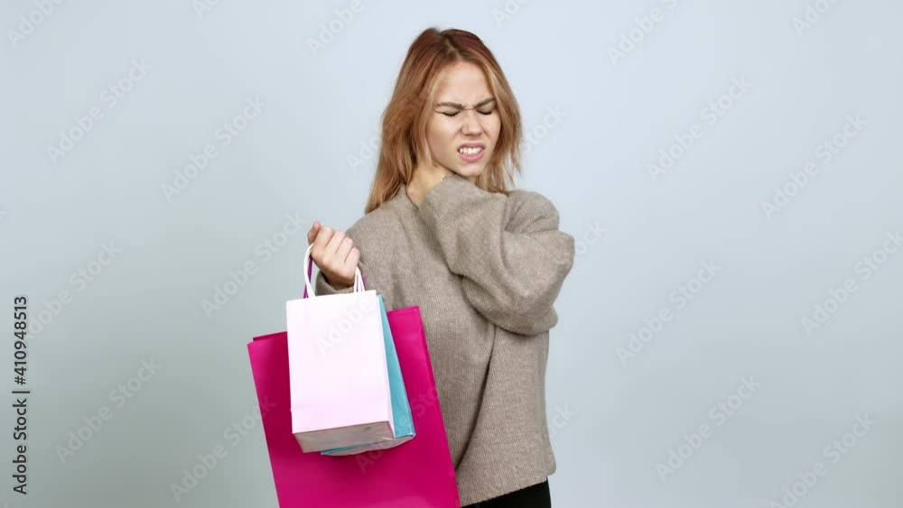 Teenager girl holding shopping bags with neck pain over isolated background Teenager girl holding shopping bags with neck pain over isolated background