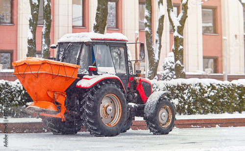 Fotografia Tractor with rock salt spreader spreading salt on driveway, prevent slippery