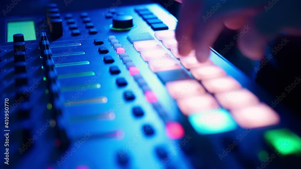 Professional DJ Plays a Beat Sampler with Color Drum Pads and Samples in Studio Environment. Beatmaker Plays edm Tracks on Party in a Nightclub. Electronic Musical Instrument. Unrecognizable person Professional DJ Plays a Beat Sampler with Color Drum Pads and Samples in Studio Environment. Beatmaker Plays edm Tracks on Party in a Nightclub. Electronic Musical Instrument. Unrecognizable person