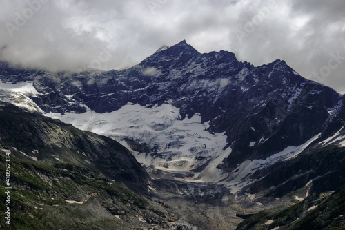 snow and a huge glacier on rocky mountains with clouds © thomaseder
