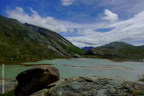 single large rock at a lake with sandy islands in the mountains