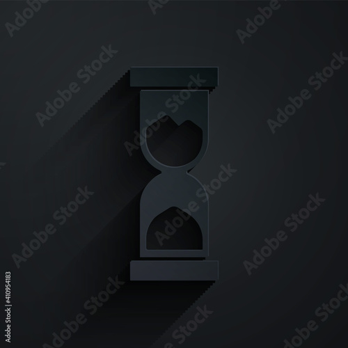 Paper cut Old hourglass with flowing sand icon isolated on black background. Sand clock sign. Business and time management concept. Paper art style. Vector.