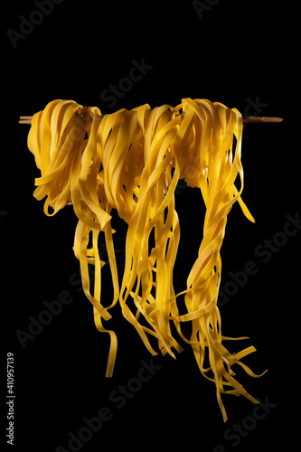 Homemade pasta rolled on a wooden stick on a dark background