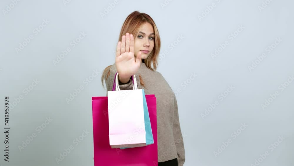 Teenager girl holding shopping bags doing stop sign over isolated background Teenager girl holding shopping bags doing stop sign over isolated background