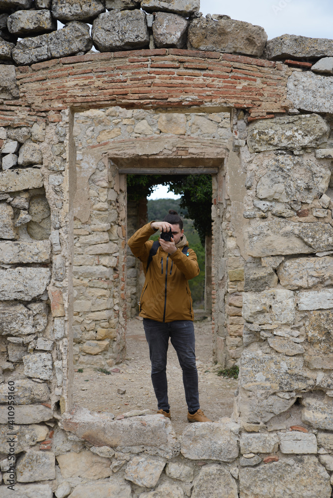 Photographer takes pictures through a window of some ruins and wall