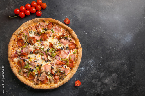 Italian pizza with tomato,mushrooms, pepperoni, onion, green bell pepper, Mozzarella cheese, sauce on black. Delivery food. View from above. Copy space.