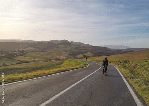 Ciclista su strada nelle colline della campagna toscana