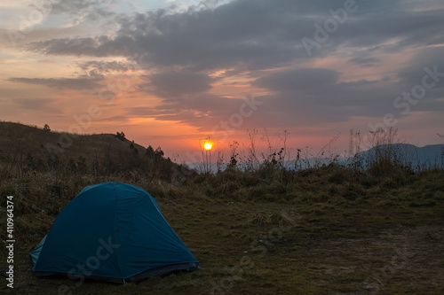 Tourist campground in the mountains in a meadow during sunrise. Hiking tour in the mountains.