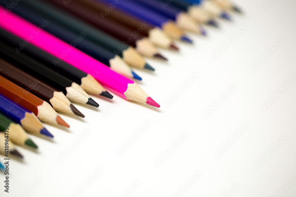 A pink coloring pen sticking out of other darker color pencils to depict being different and leadership. A pink coloring pen sticking out of other darker color pencils to depict being different and leadership.
