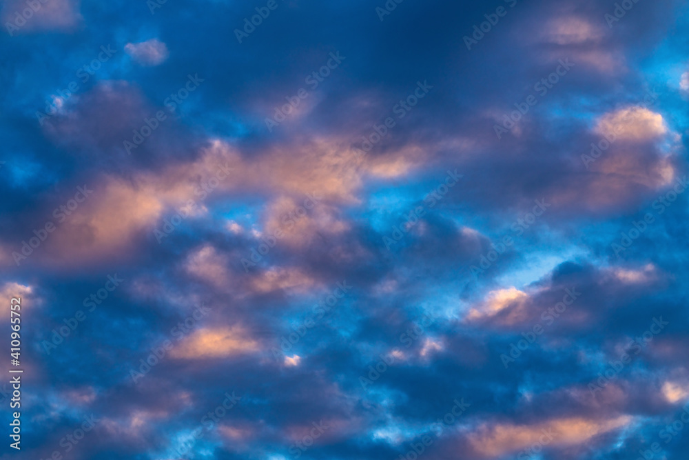 Amazing clouds in blue sky, illuminated by rays of sun at sunset to change weather. Soft focus, motion blur colorful abstract cloudscape background.