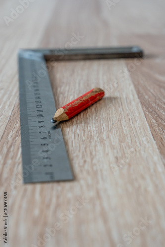Red Carpenter's Pencil and Right Angle's Tool on Laminate Floor © Reinholds