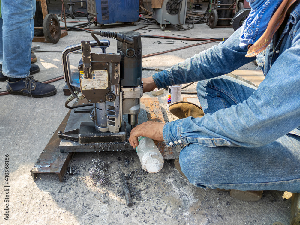 Worker are using a drilling machine to drill a hole on steel plate at industrial factory. Worker are using a drilling machine to drill a hole on steel plate at industrial factory.