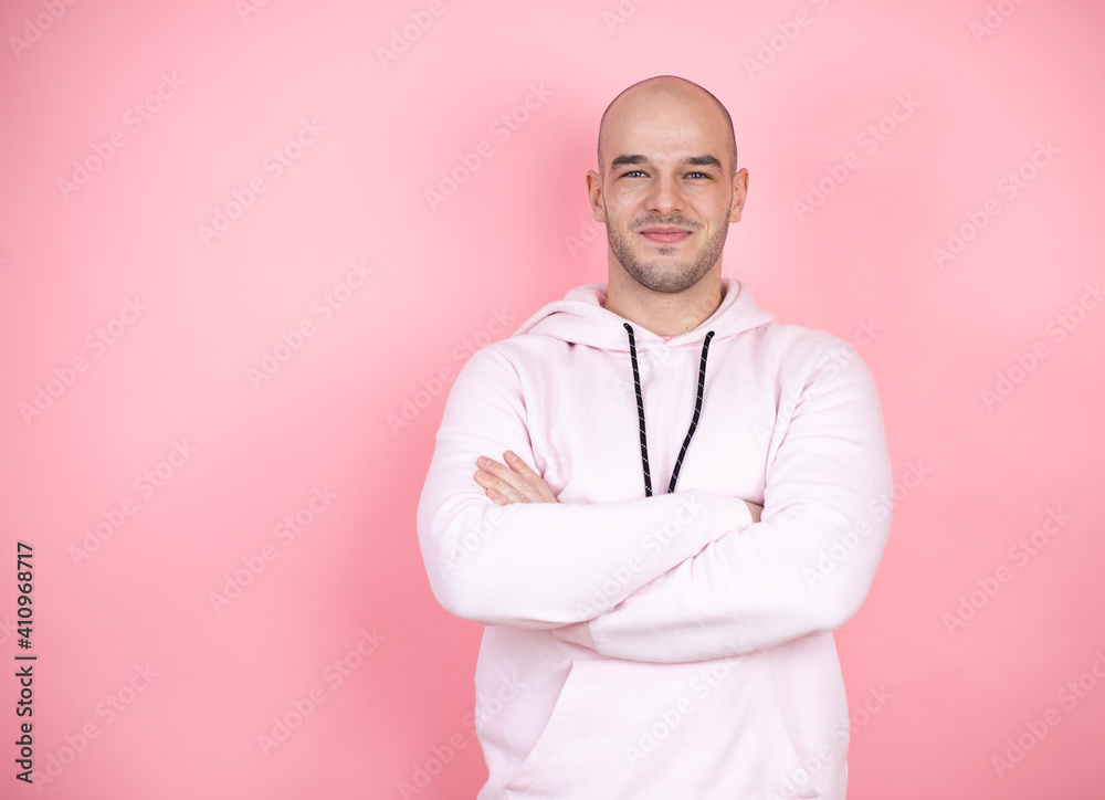 Young bald man wearing casual sweatshirt over pink isolated background with a happy face standing and smiling with a confident smile showing teeth with arms crossed Young bald man wearing casual sweatshirt over pink isolated background with a happy face standing and smiling with a confident smile showing teeth with arms crossed