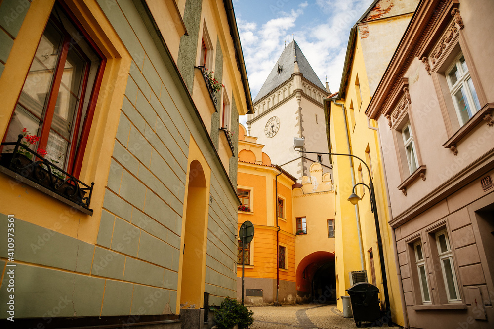 Narrow medieval street with baroque and renaissance historical buildings, sunny summer day, gothic clock tower of Town hall with Hussitism museum, Tabor, South Bohemia, Czech Republic