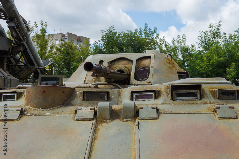 The tower with a cannon and a machine gun of the Soviet armored personnel carrier. Against a background of blue sky with clouds Details of military equipment. Close-up