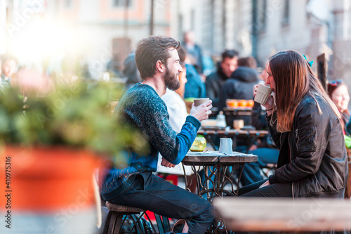 Hipster friends drinking coffee in Stockholm old town - Young couple sitting face to face outdoors and enjoying time together