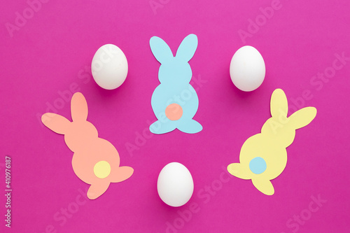 Easter bunny decoration. Paper cut DIY holiday colorful rabbits and white easter eggs .Top view,  copy space on pink  background.