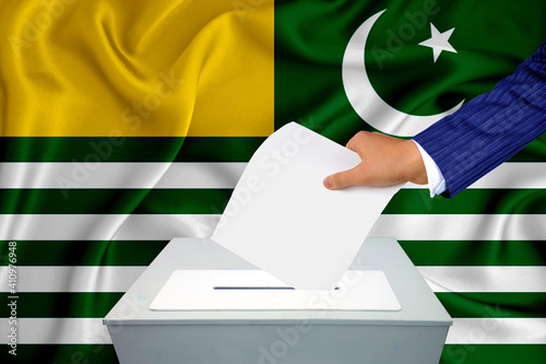 Elections in the country - voting at the ballot box. A man's hand puts his vote into the ballot box. Flag azad kashmir on background. photo