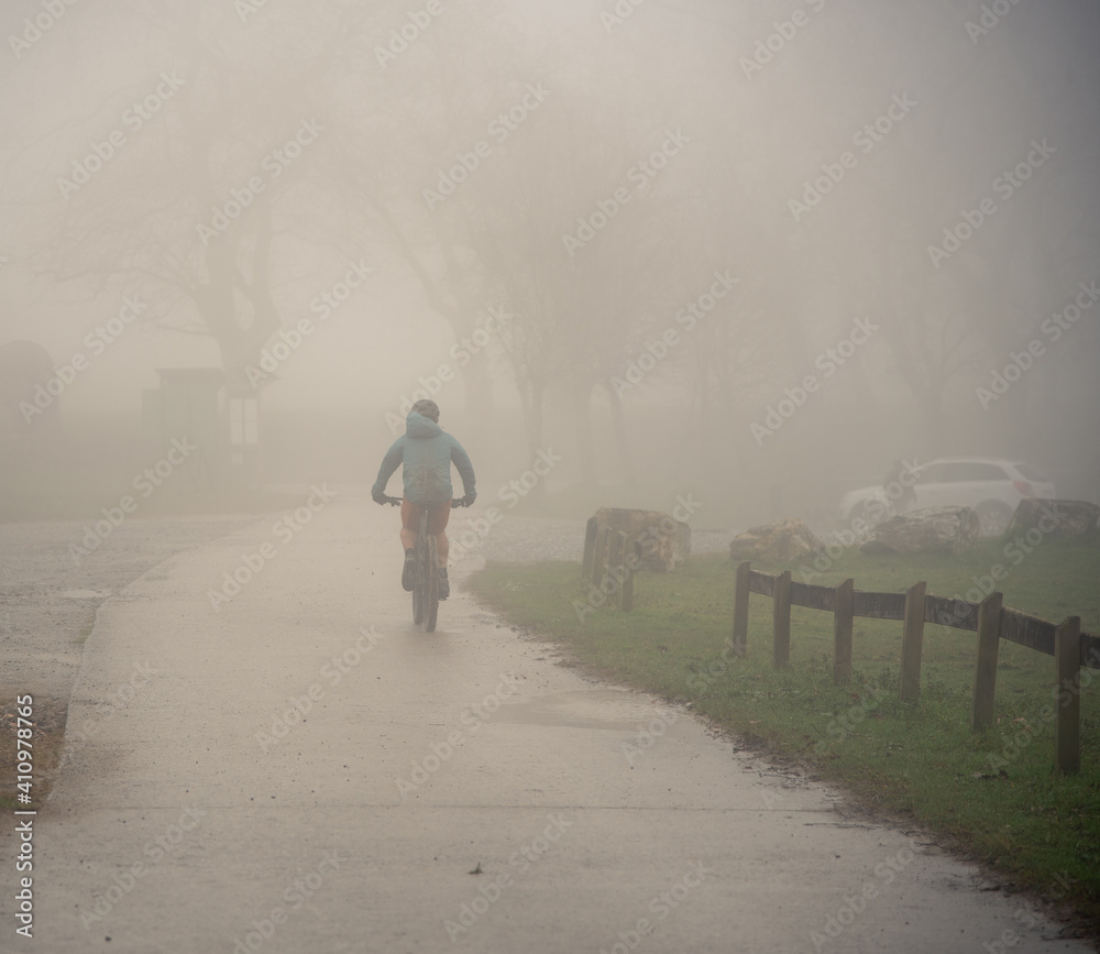 Un ciclista paseando por la montaña con niebla. 