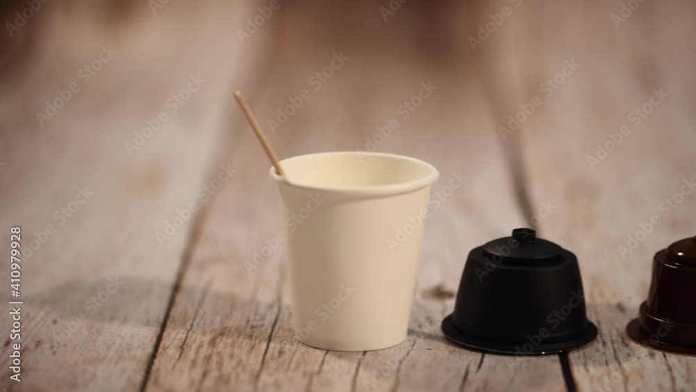 Taza de café con cápsulas sobre mesa de madera.
