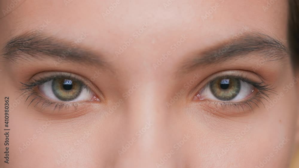 Extreme close-up of young woman opens her eyes and looks at camera Extreme close-up of young woman opens her eyes and looks at camera