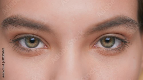 Extreme close-up of young woman opens her eyes and looks at camera photo