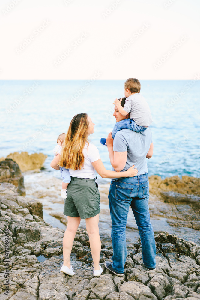Mother and father holding their children while having a family day at the rocky beach