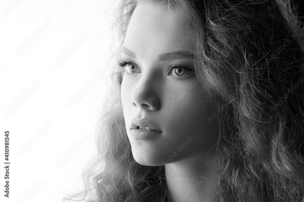 Fototapeta premium Curly girl on white background. Black and white portrait of beautiful young woman. Free space for text.