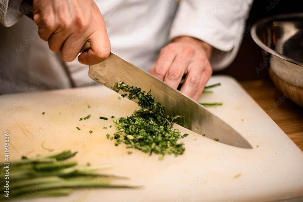 Close-up of hands of chef chopping green onion with knife on cutting board Close-up of hands of chef chopping green onion with knife on cutting board